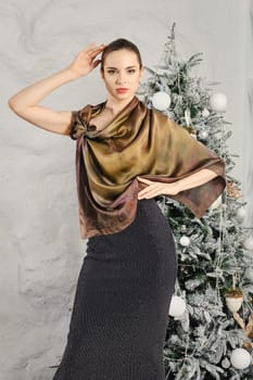 Beautiful and touchy young woman posing in silk scarf over the glitter dress