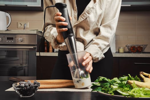 Hands of unrecognizable woman using blender to make smoothie