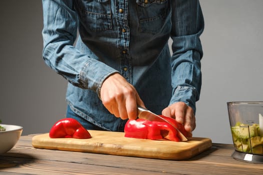 Female hands slicing red bell pepper with kitchen knife