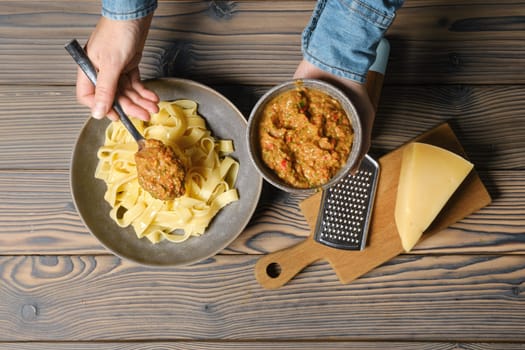 Top view of hands of unrecognizable woman serve vegetable sauce in plate with pasta