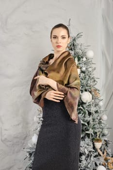 Cute young woman posing in silk scarf over the glitter dress
