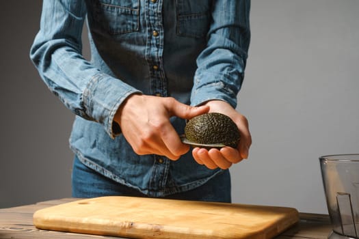 Close up of woman hands cutting fresh avocado with knife in the kitchen