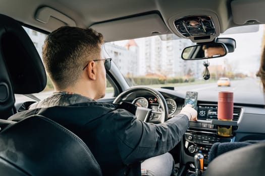 A man uses a phone installed in the holder while driving.