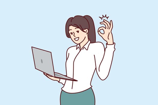 Woman CEO of company stands with laptop in hands and shows OK gesture, giving consent to plan proposed by employees. Businesswoman performs duties of CEO director and looks at screen smiling