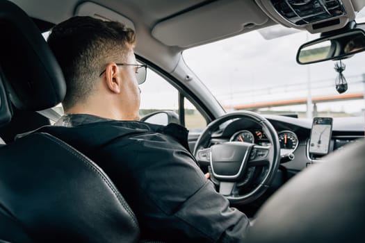 A man drives a car using a navigation application installed on a smartphone.