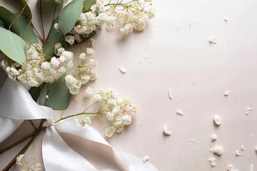 Styled stock photo. Feminine wedding desktop mockup with baby's breath Gypsophila flowers, dry green eucalyptus leaves, satin ribbon and white background. Empty space. Top view. Picture for blog.