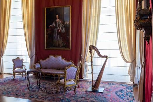 Venaria Reale, Italy - February 2023: luxury interior, old Royal Palace. Perspective with harp, window and baroque decoration.