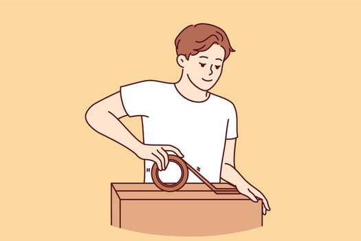 Man packs personal belongings into cardboard relocation box and seals lid with tape. Positive guy small business owner holding box and preparing goods ordered by customer for shipment
