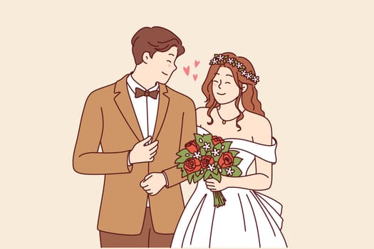 Wedding ceremony at bride and groom in beautiful outfits holding hands during engagement in church. Woman with bouquet flowers stands near husband at wedding ceremony, posing together for family photo