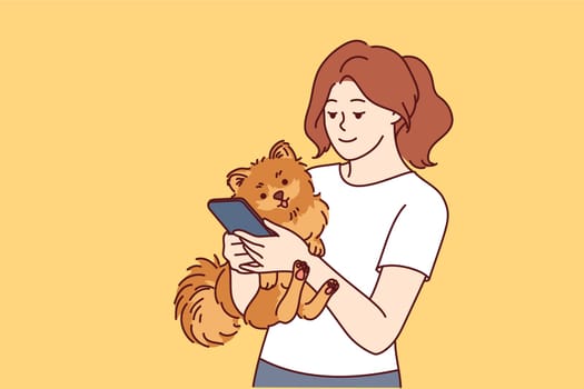 Woman has small dog and phone in hands, and is looking on internet for hotel or cafe to relax with pet. Caring girl with dog calls veterinarian to make appointment for vaccinations