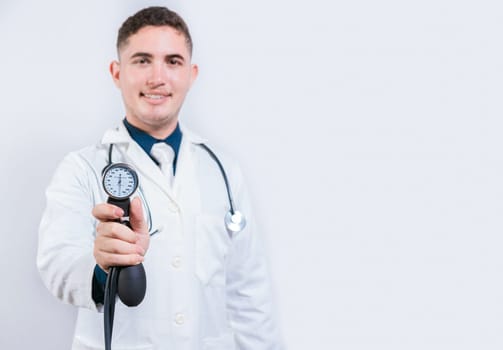 Young doctor holding tensiometer on isolated background. Latin doctor showing blood pressure monitor isolated
