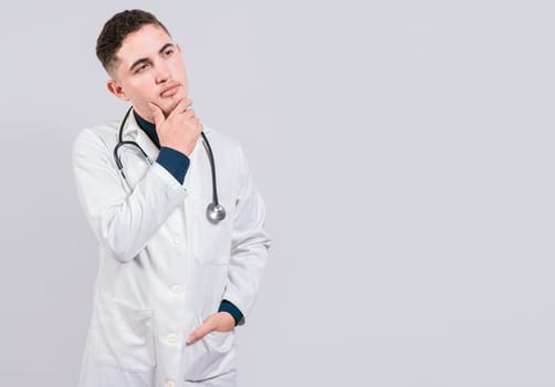 Doctor thinking with hand on chin. Pensive doctor man looking up, Young doctor thinking and looking up isolated