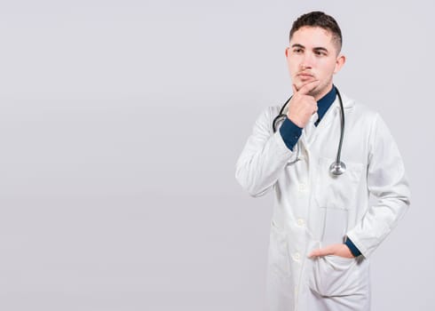 Pensive doctor man looking up. Young doctor thinking and looking up isolated, Doctor thinking with hand on chin