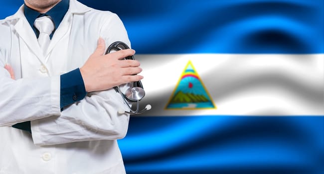 Doctor with stethoscope on flag of Nicaragua. Health and care concept with Nicaragua flag. Doctor with crossed arms on flag of Nicaragua