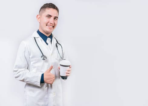 Satisfied doctor holding takeaway coffee isolated. Young doctor holding a coffee to go isolated. Smiling doctor holding coffee with thumb up