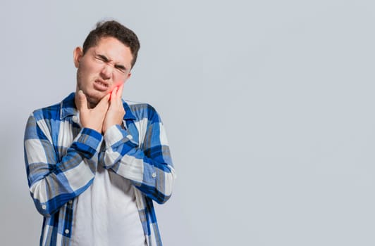 Man suffering with toothache or pulpitis. Concept of people suffering from toothache, Young man with sensitivity and toothache isolated. Tooth pain and sensitivity in people