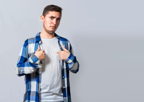 Confused caucasian young man pointing at himself. Confused person pointing at himself isolated. Confused latin guy pointing at himself isolated, Portrait of confused teenager pointing at himself