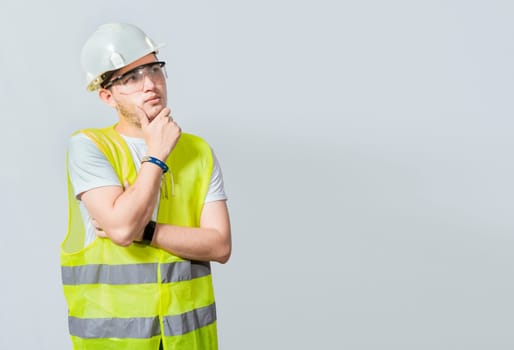 A pensive engineer on white background. Concept of a meditative engineer solated. Pensive builder man with hand on chin, Portrait of young builder thinking with hand on chin isolated
