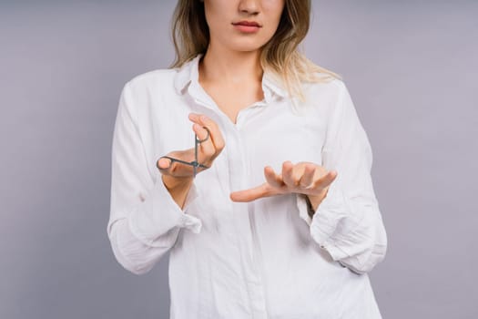 Woman with a scissors having hair cut. Amazed female with straight hair, scissor. Haircare concept.