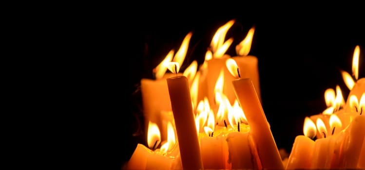 Religious candle light on black background. Yellow candlelight flame in dark christian church at night. Christian religion worship.