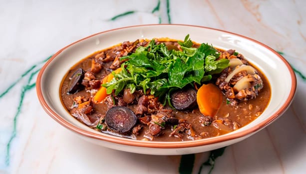 Brazilian feijoada dumplings with crackling garnish and decorated with orange chips