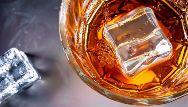 Glass of whiskey with ice on black stone table. Top view with copy space