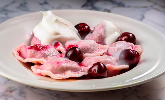 The macro photo of cherry dumplings covered with sour cream with steam in a plate on a white mar