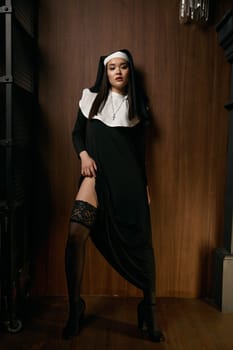 Beautiful sensual woman in nun robe seducing with passionate view showing perfect legs in sexual lingerie