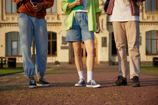 Group of smart students standing outdoors at campus. High school university youth community. Crop shot