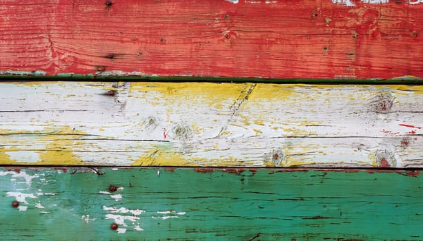 Texture of vintage wood boards with cracked paint of white, red, yellow and blue color. Horizontal retro background with wooden planks of different colors
