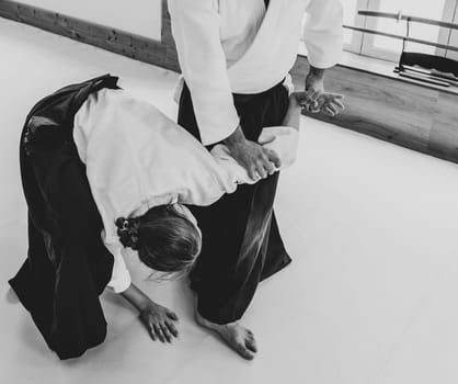 People practicing aikido martial art in a dojo background.