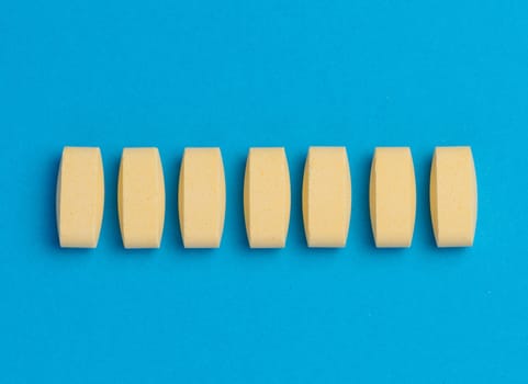 Yellow oval tablets on a blue background, top view