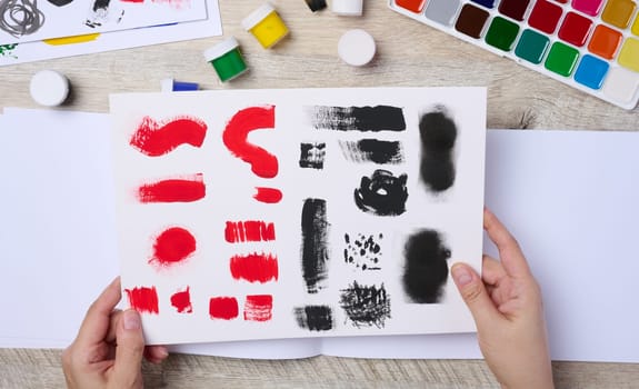 Set of watercolor paints, brushes and paper with different strokes and colors.