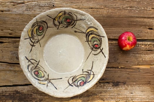 empty bowl and fresh apple on wooden background - handmade pottery