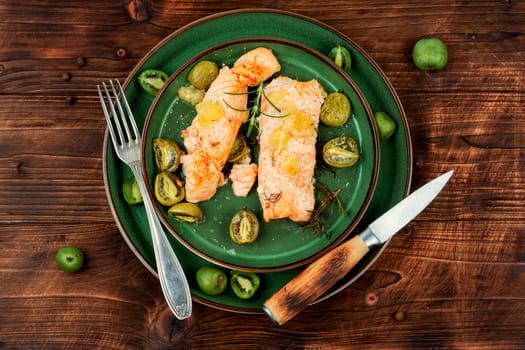 Salmon steaks grilled with mini kiwi on rustic wooden table. Top view.