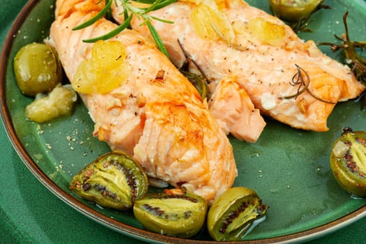 Salmon steaks grilled with mini kiwi on rustic wooden table. Top view.
