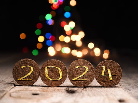 Bottle cork with the inscription 2024 on colorful Christmas lights background