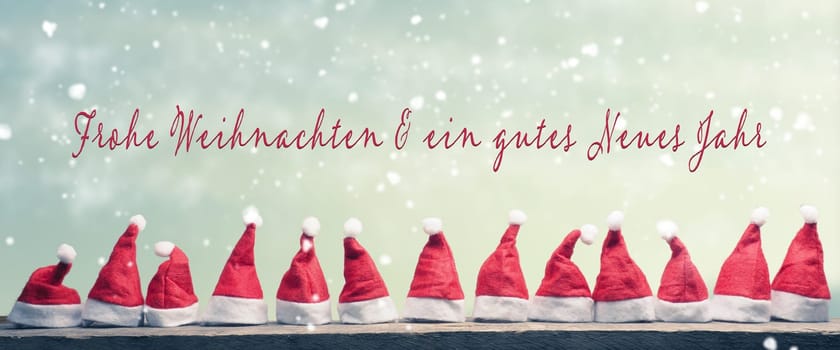 Many hats of Santa in a row on a rustic wooden table with the German words Merry Christmas and a happy New Year, panoramic view