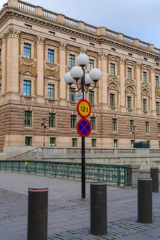 lantern pole with traffic shields in Stockholm, Sweden. In the background the swedish parliament building.