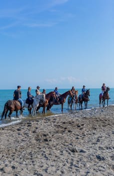 Policoro, Italy - 7 May 2023: People riding horses in a Policoro beach, Basilicata, southern Italy.