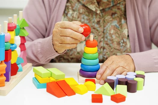 Asian elderly woman playing puzzles game for treatment dementia prevention and Alzheimer disease.