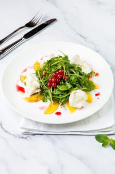 green salad with arugula and lingonberries on a white plate