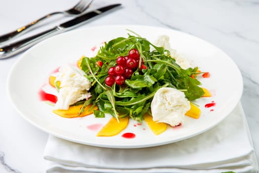 green salad with arugula and lingonberries on a white plate