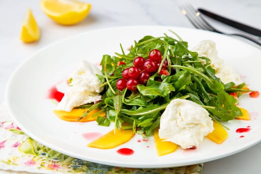 green salad with arugula and lingonberries on a white plate