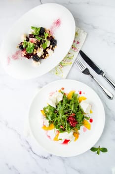green salad with arugula and lingonberries on a white plate