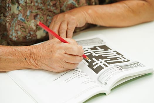 Bangkok, Thailand - May 15, 2022 elderly woman playing sudoku puzzle game for treatment dementia prevention and Alzheimer disease.