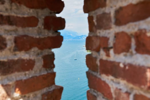 View of Lake Garda from the old town in Malcesine through a gap in a wall