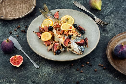 Baked gilt head bream, dorado fish with almonds and figs on rural wooden table. Autumn recipe.
