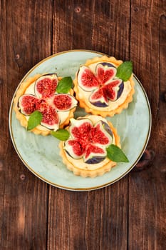 Appetizing tartlet dessert with whipped cream and figs. Delicious fig pie.