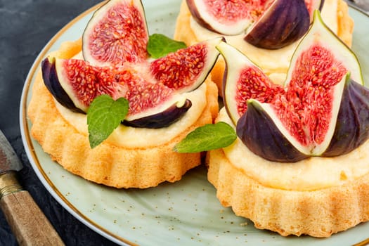 Appetizing tartlet dessert with whipped cream and figs. Delicious fig pie.